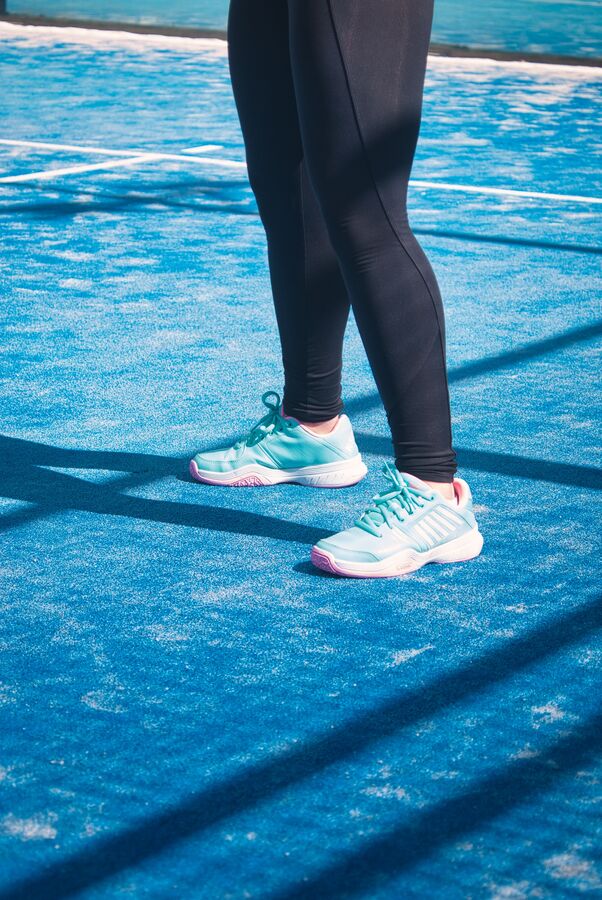Türkise Padel-Schuhe auf blauem Court