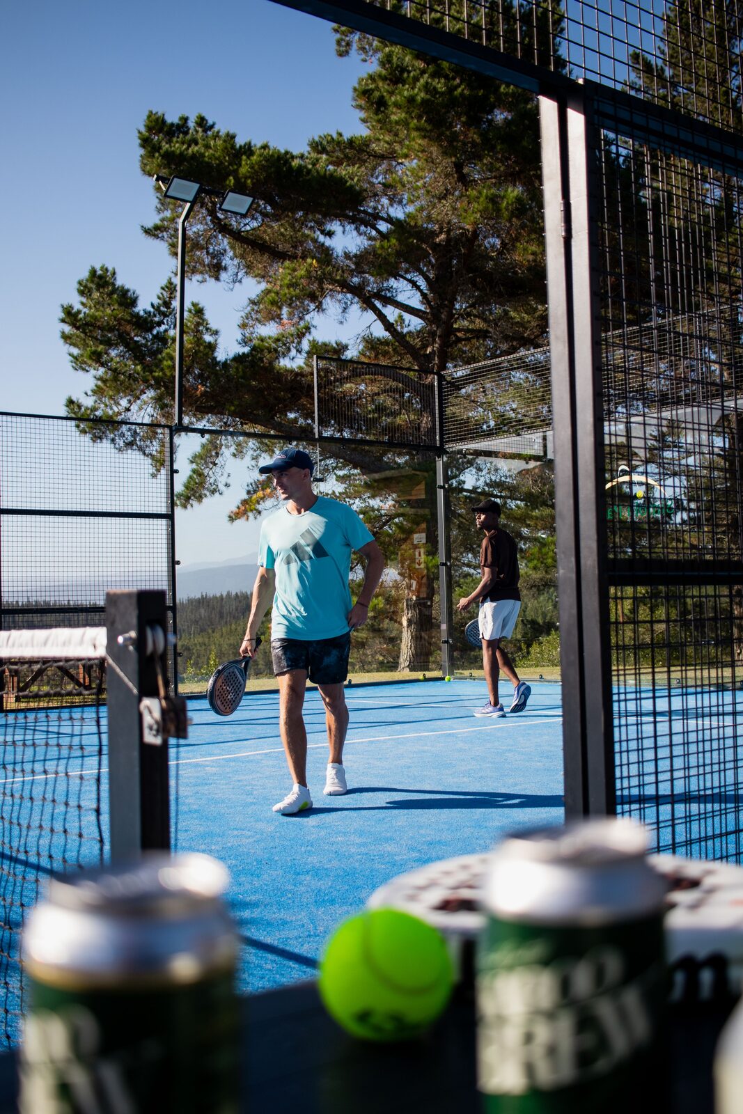 Padelspieler beim Aufschlag auf einem roten Court