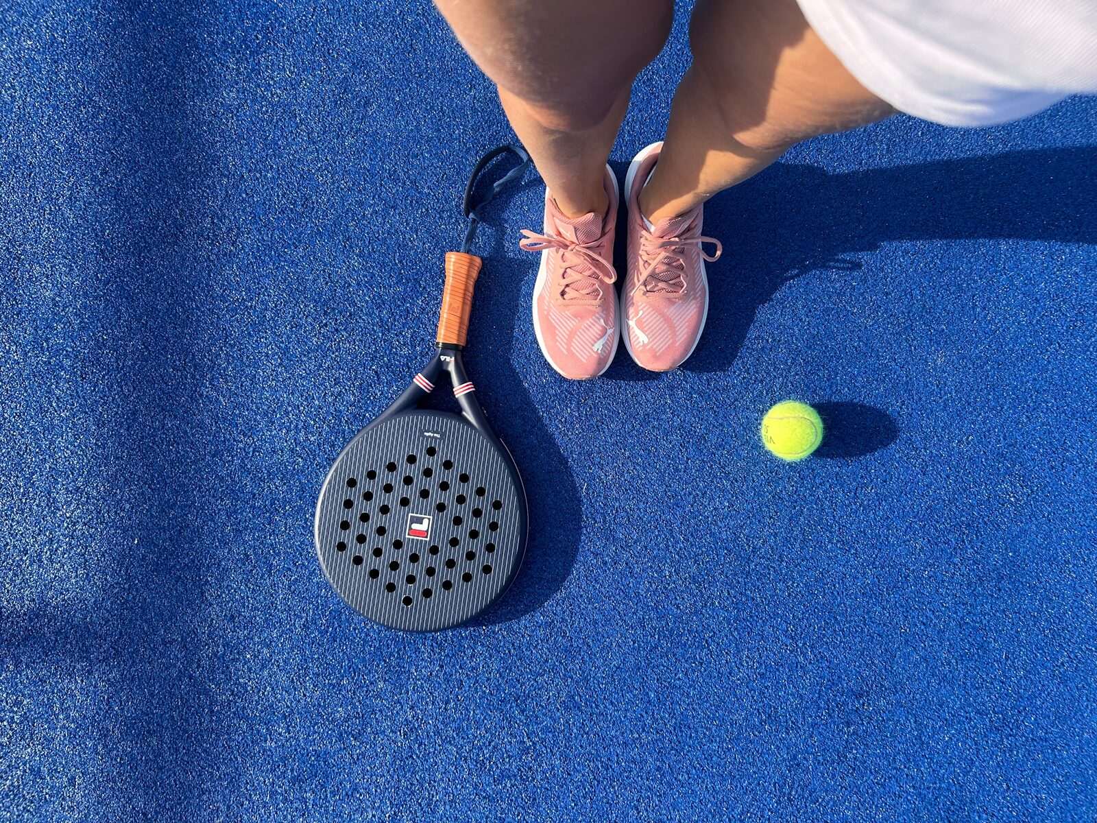 Zwei Spieler unterhalten sich locker auf dem Padel-Court, im Vordergrund stehen Getränkedosen